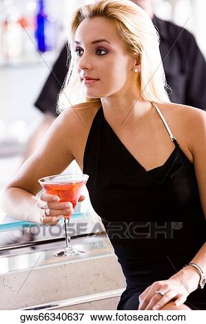 Close-up of a young woman holding a glass of martini View Large Photo Image Stock Photo - Close-up of a young woman holding a glass of martini. Fotosearch