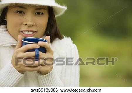 Stock Photograph - Close-up of a young woman holding a coffee cup. Fotosearch