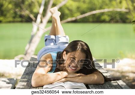 Close-up of a young woman lying on a bench reading a book View Large Photo Image Picture - Close-up of a young woman lying on a bench reading a book. Fotosearch