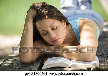 Close-up of a young woman lying on a bench reading a book View Large Photo Image Stock Image - Close-up of a young woman lying on a bench reading a book. Fotosearch