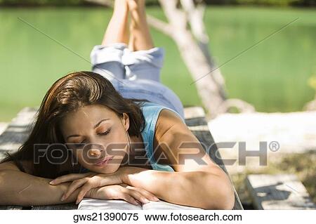 Close-up of a young woman lying on a bench reading a book View Large Photo Image Stock Photography - Close-up of a young woman lying on a bench reading a book. Fotosearch