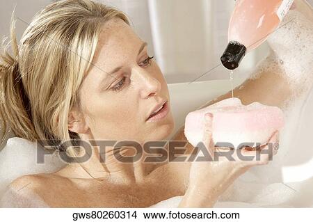 Close-up of a young woman pouring soap on a bath sponge View Large Photo Image Picture - Close-up of a young woman pouring soap on a bath sponge. Fotosearch
