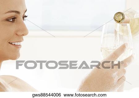 Close-up of a young woman pouring white wine into a wineglass View Large Photo Image Stock Photograph - Close-up of a young woman pouring white wine into a wineglass. Fotosearch