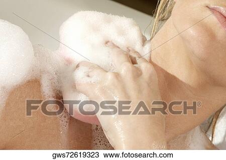 Close-up of a young woman scrubbing her shoulder with a bath sponge View Large Photo Image Stock Image - Close-up of a young woman scrubbing her shoulder with a bath sponge. Fotosearch