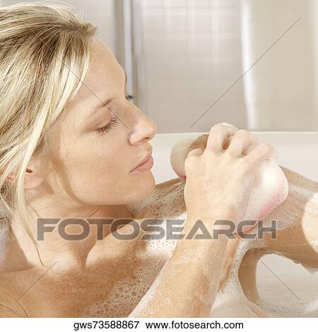 Close-up of a young woman scrubbing her shoulder with a bath sponge View Large Photo Image Stock Photo - Close-up of a young woman scrubbing her shoulder with a bath sponge. Fotosearch