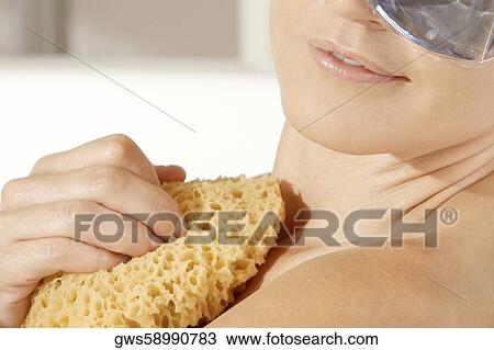 Close-up of a young woman scrubbing herself with a bath sponge in a bathtub View Large Photo Image Stock Image - Close-up of a young woman scrubbing herself with a bath sponge in a bathtub. Fotosearch