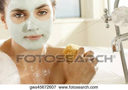 Stock Photo - Close-up of a young woman scrubbing herself with a sponge. Fotosearch