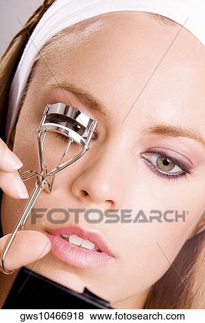Close-up of a young woman shaping her eyelashes with an eyelash curler View Large Photo Image Stock Photo - Close-up of a young woman shaping her eyelashes with an eyelash curler. Fotosearch