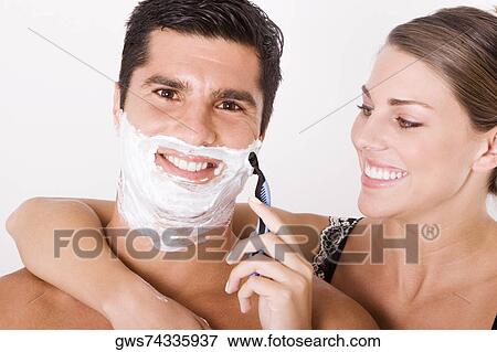 Stock Photo - Close-up of a young woman shaving a mid adult man's face. Fotosearch