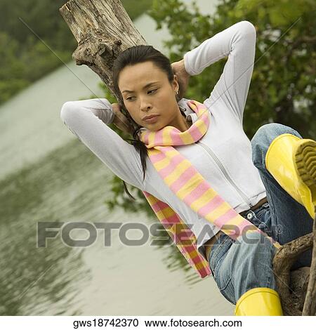 Close-up of a young woman sitting on a tree stump by the lake View Large Photo Image Stock Image - Close-up of a young woman sitting on a tree stump by the lake. Fotosearch