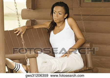 Close-up of a young woman sitting on a porch swing View Large Photo Image Stock Photo - Close-up of a young woman sitting on a porch swing. Fotosearch