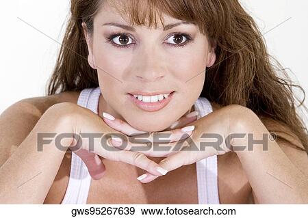 Close-up of a young woman smiling with her hands on her chin View Large Photo Image Stock Photo - Close-up of a young woman smiling with her hands on her chin. Fotosearch