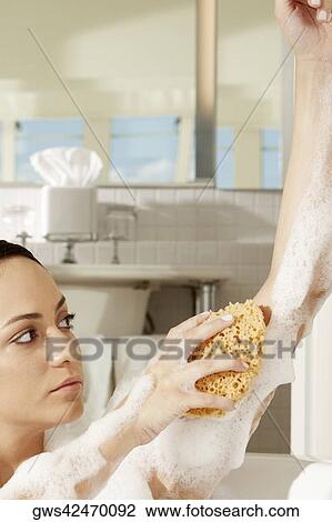 Close-up of a young woman using a bath sponge on her arm View Large Photo Image Stock Image - Close-up of a young woman using a bath sponge on her arm. Fotosearch