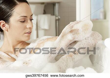 Close-up of a young woman using a bath sponge on her arm View Large Photo Image Stock Photograph - Close-up of a young woman using a bath sponge on her arm. Fotosearch