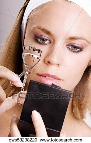 Close-up of a young woman using an eyelash curler View Large Photo Image Stock Image - Close-up of a young woman using an eyelash curler. Fotosearch