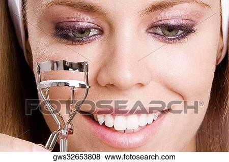 Close-up of a young woman using an eyelash curler View Large Photo Image Stock Photo - Close-up of a young woman using an eyelash curler. Fotosearch