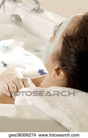 Close-up of a young woman wearing a facial mask in a bathtub View Large Photo Image Picture - Close-up of a young woman wearing a facial mask in a bathtub. Fotosearch