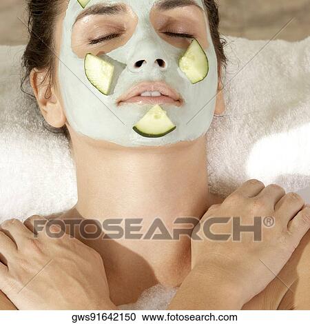 Stock Image - Close-up of a young woman wearing a facial mask in a bathtub. Fotosearch