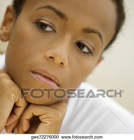 Stock Image - Close-up of a young woman with her hands under her chin. Fotosearch