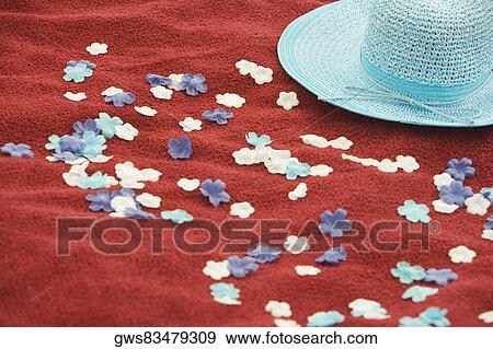 Stock Photo - Close-up of artificial flowers with a hat on a picnic blanket. Fotosearch