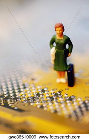 Stock Photo - Close-up of the figurine of a woman with a briefcase on a circuit board. Fotosearch