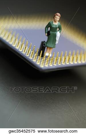 Stock Photography - Close-up of the figurine of a woman with a briefcase on a computer chip. Fotosearch
