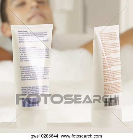 Close-up of two bottles of moisturizer with a young man in a bathtub behind it View Large Photo Image Picture - Close-up of two bottles of moisturizer with a young man in a bathtub behind it. Fotosearch