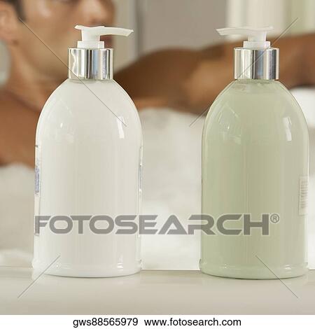 Close-up of two bottles of moisturizer with a young man in a bathtub behind it View Large Photo Image Stock Photo - Close-up of two bottles of moisturizer with a young man in a bathtub behind it. Fotosearch
