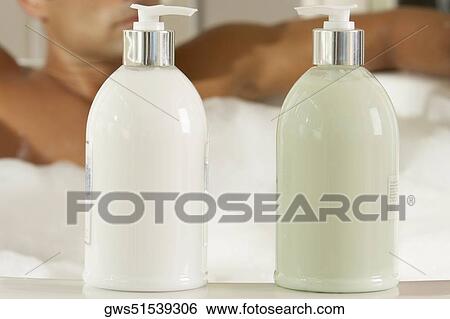 Close-up of two bottles of moisturizer with a young man in a bathtub behind it View Large Photo Image Stock Photograph - Close-up of two bottles of moisturizer with a young man in a bathtub behind it. Fotosearch