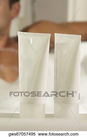 Close-up of two bottles of moisturizer with a young man in a bathtub behind it View Large Photo Image Stock Photography - Close-up of two bottles of moisturizer with a young man in a bathtub behind it. Fotosearch