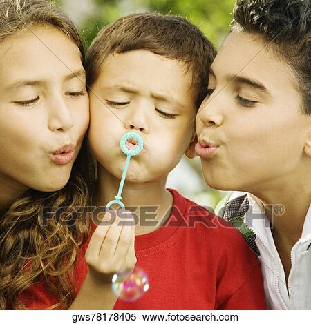 Close-up of two boys and a girl blowing bubble with a bubble wand View Large Photo Image Stock Photography - Close-up of two boys and a girl blowing bubble with a bubble wand. Fotosearch