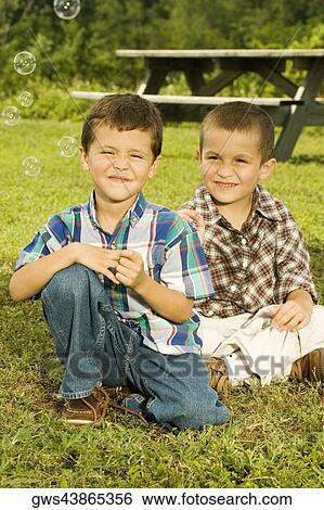 Close-up of two boys sitting in the garden smiling View Large Photo Image Stock Photograph - Close-up of two boys sitting in the garden smiling. Fotosearch