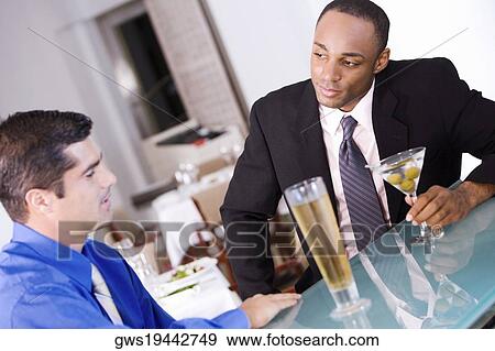 Close-up of two businessmen sitting at a bar counter View Large Photo Image Stock Photo - Close-up of two businessmen sitting at a bar counter. Fotosearch