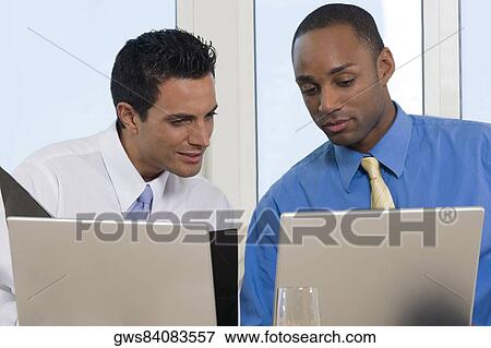 Close-up of two businessmen working in front of laptops View Large Photo Image Stock Photo - Close-up of two businessmen working in front of laptops. Fotosearch