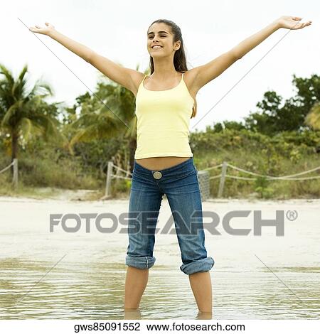 Girl standing on the beach with her arms outstretched View Large Photo Image Stock Image - Girl standing on the beach with her arms outstretched. Fotosearch