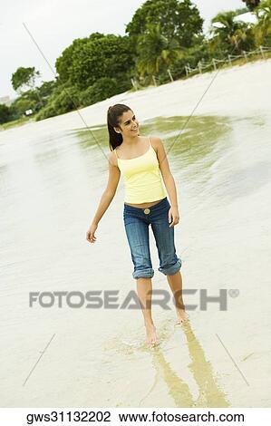 Girl wading in water on the beach View Large Photo Image Stock Image - Girl wading in water on the beach. Fotosearch