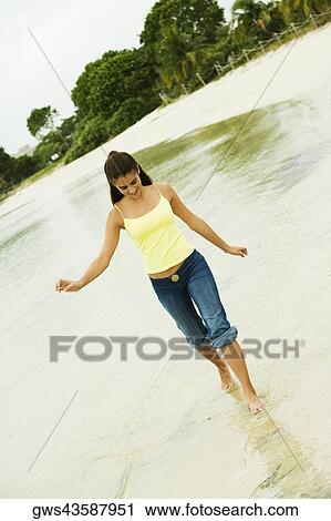 Girl wading in water on the beach View Large Photo Image Stock Image - Girl wading in water on the beach. Fotosearch