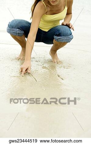 Girl writing in sand with her finger View Large Photo Image Stock Photo - Girl writing in sand with her finger. Fotosearch
