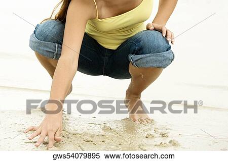 Stock Photography - Girl writing in sand with her finger. Fotosearch