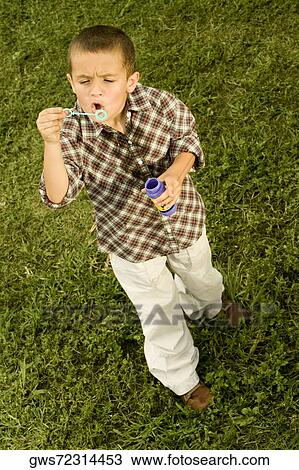 High angle view of a boy blowing bubbles with a bubble wand View Large Photo Image Stock Image - High angle view of a boy blowing bubbles with a bubble wand. Fotosearch