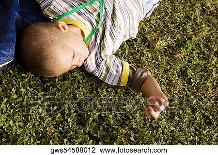 Stock Image - High angle view of a boy lying on the grass. Fotosearch