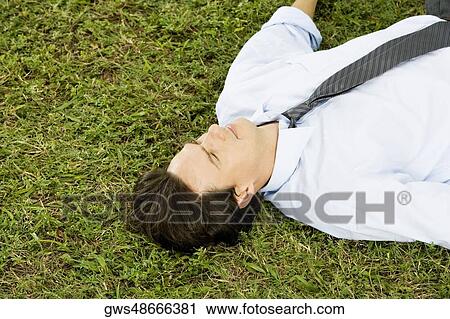 High angle view of a businessman lying on the grass View Large Photo Image Stock Image - High angle view of a businessman lying on the grass. Fotosearch