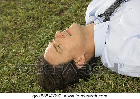 High angle view of a businessman lying on the grass View Large Photo Image Stock Image - High angle view of a businessman lying on the grass. Fotosearch