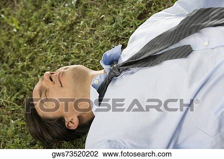 High angle view of a businessman lying on the grass View Large Photo Image Stock Image - High angle view of a businessman lying on the grass. Fotosearch