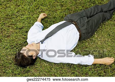 High angle view of a businessman lying on the grass View Large Photo Image Stock Photography - High angle view of a businessman lying on the grass. Fotosearch