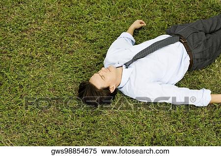 High angle view of a businessman lying on the grass View Large Photo Image Stock Photography - High angle view of a businessman lying on the grass. Fotosearch