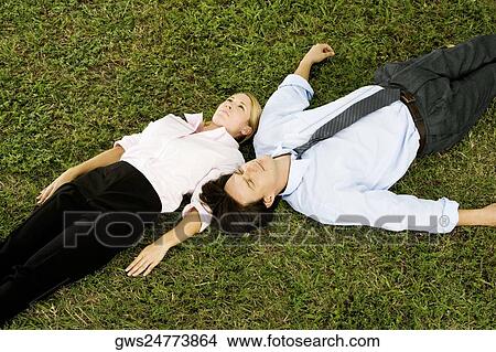 High angle view of a businesswoman and a businessman lying on the grass View Large Photo Image Picture - High angle view of a businesswoman and a businessman lying on the grass. Fotosearch