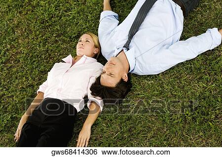 High angle view of a businesswoman and a businessman lying on the grass View Large Photo Image Stock Photograph - High angle view of a businesswoman and a businessman lying on the grass. Fotosearch