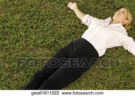 Stock Image - High angle view of a businesswoman lying on the grass. Fotosearch