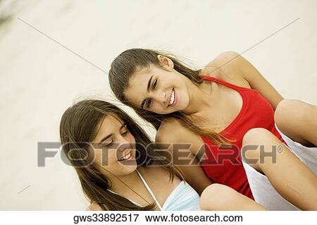 High angle view of a girl and a teenage girl sitting together on the beach smiling View Large Photo Image Stock Photo - High angle view of a girl and a teenage girl sitting together on the beach smiling. Fotosearch